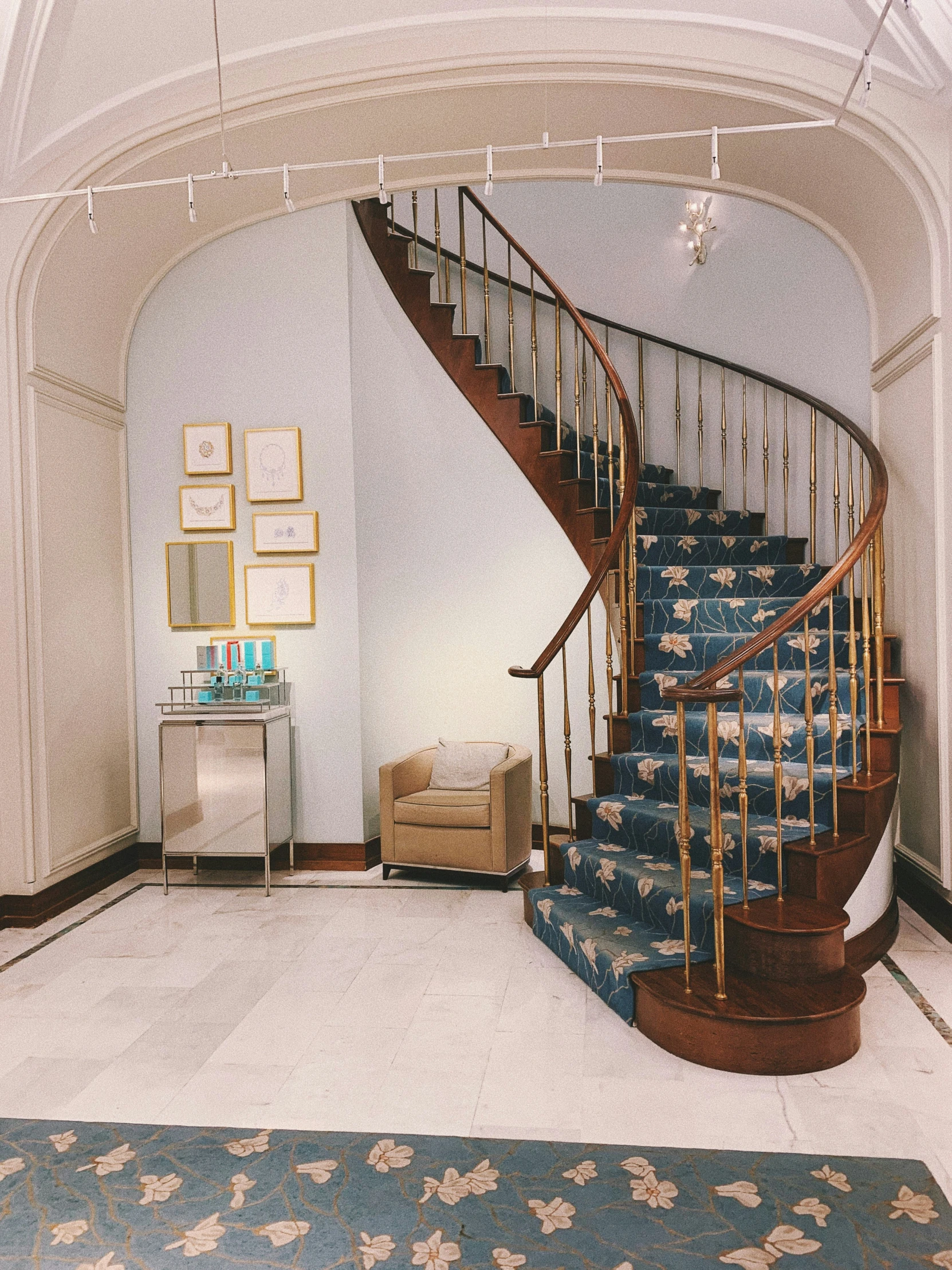 a white hall with a blue stair case and a blue rug