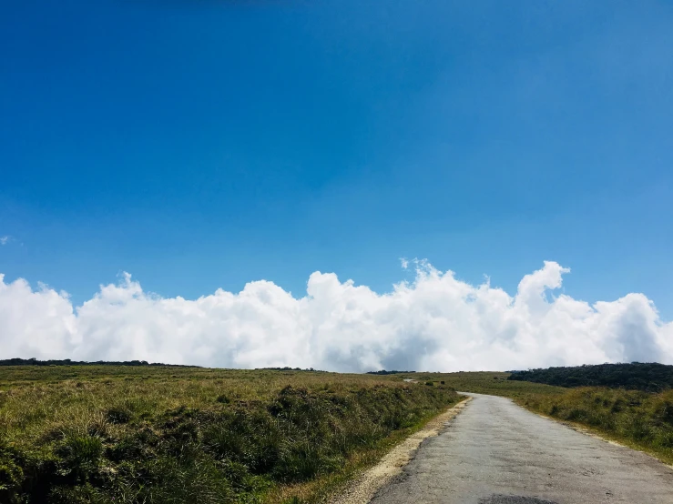 an empty rural road under cloudy blue skies