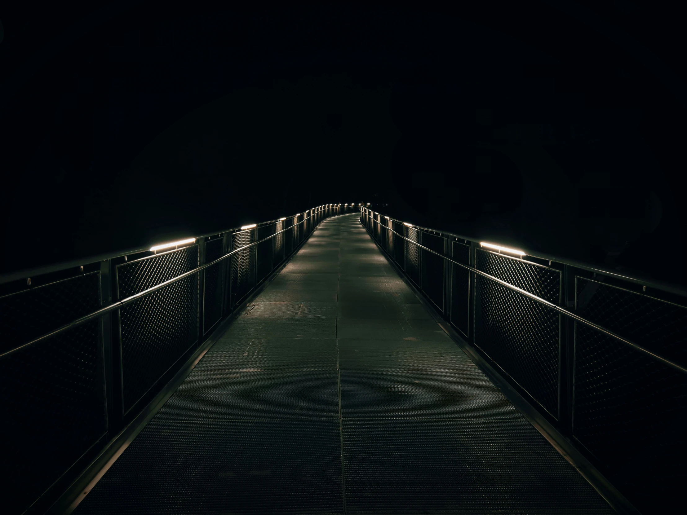 the walkway is dimly lit at night in the dark