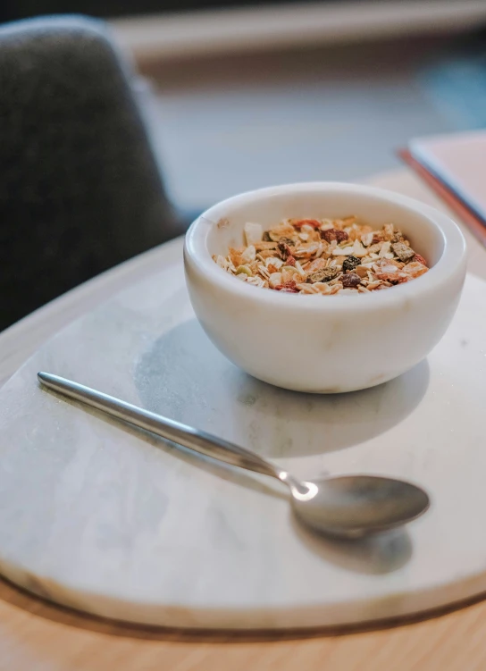 a bowl with granola on a plate with a spoon