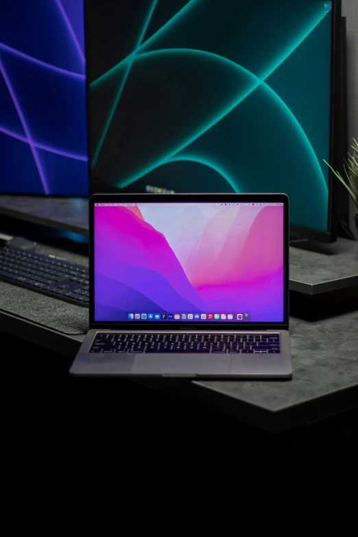 an apple laptop sits next to another apple monitor