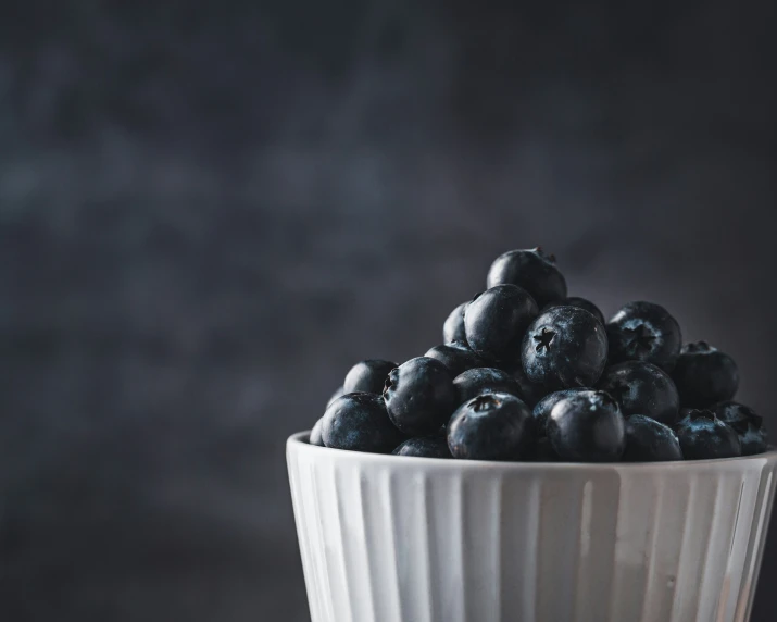 some blueberries are in a white bowl