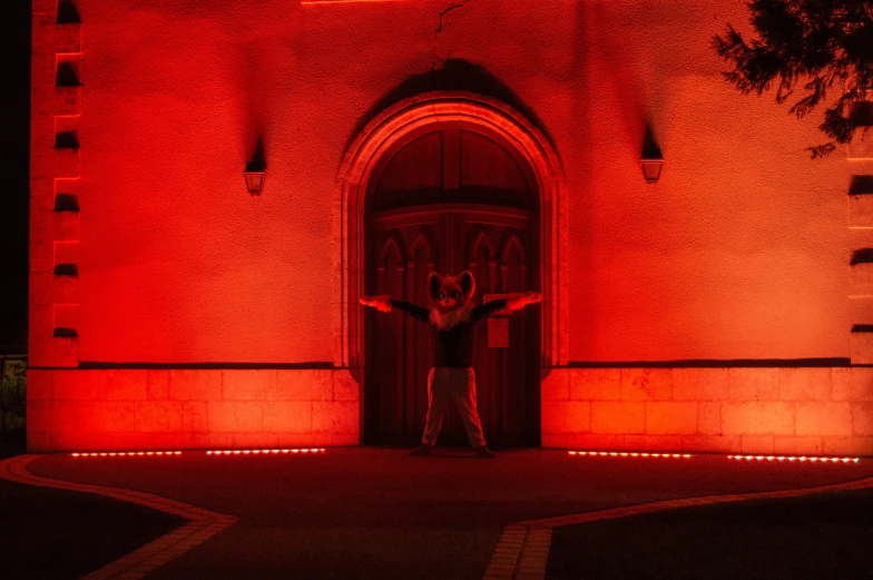 man standing in front of door at night with red light