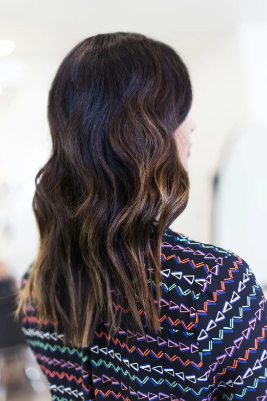 woman with shoulder length wavy hair in front of mirror