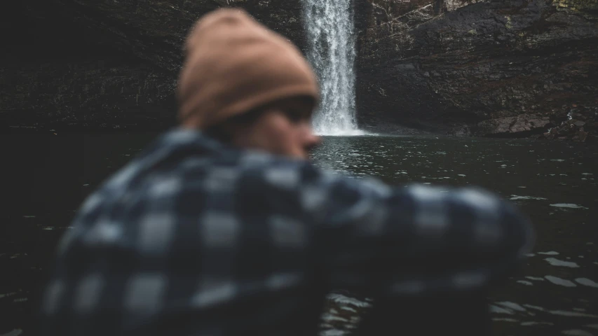 man with head turned and waterfall in the background