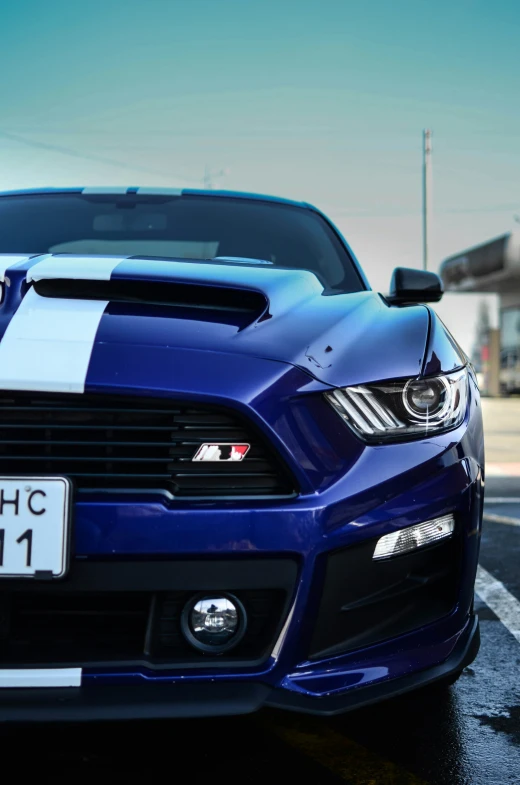 a blue mustang mustang car in a lot with a sky background