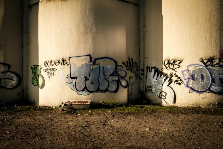 two concrete pillars covered in graffiti under an open air structure