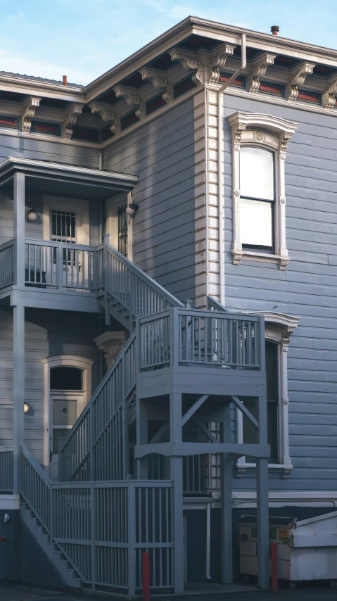 a gray building with a porch and a large stairway