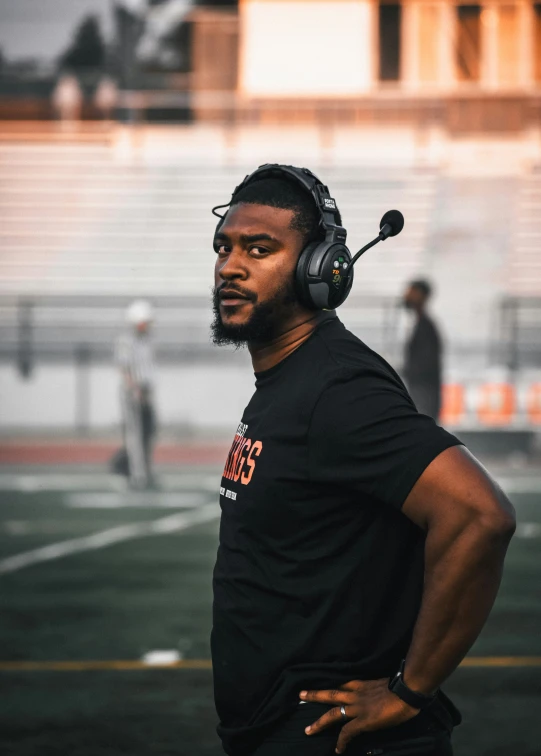 man standing on a football field wearing headphones