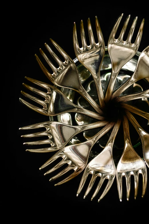 forks are arranged around a metal bowl in the dark