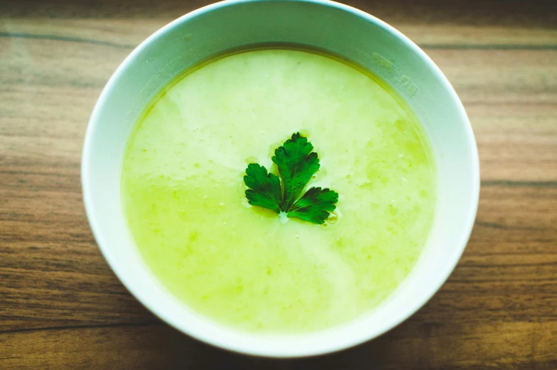 a small fresh green leaf resting on a bowl of soup