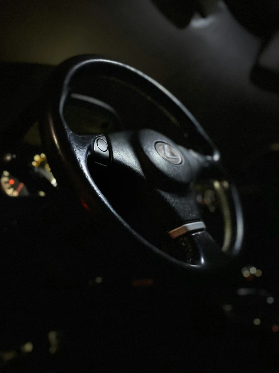 a black steering wheel and a car dashboard in the darkness