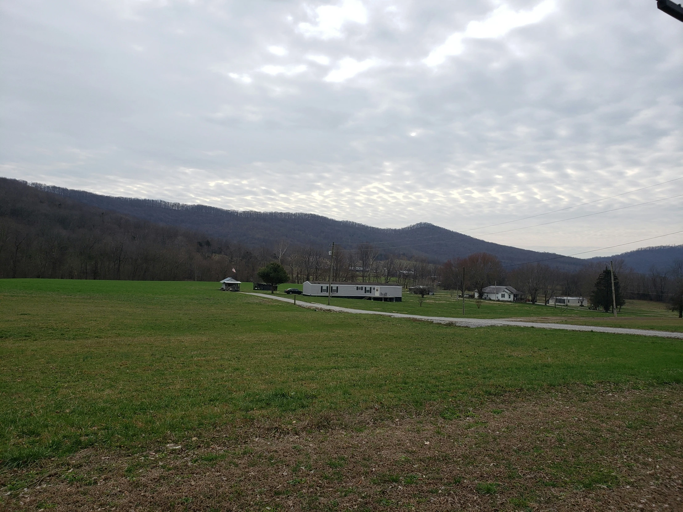 a field and dirt path in front of mountain view