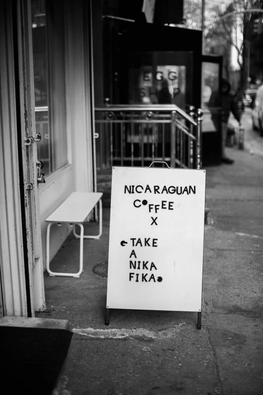 black and white pograph of a sign on a sidewalk