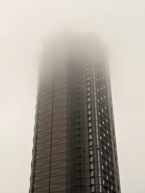a very tall building in the city shroud by fog