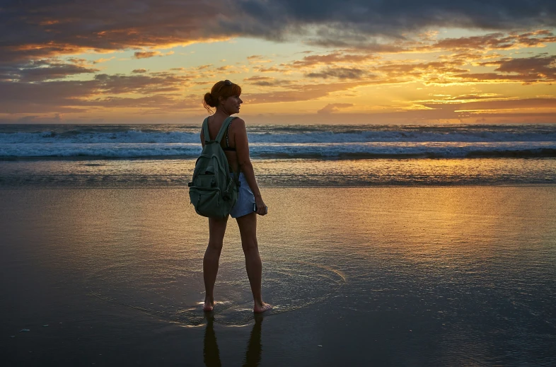 a girl standing on the beach looking out to the water