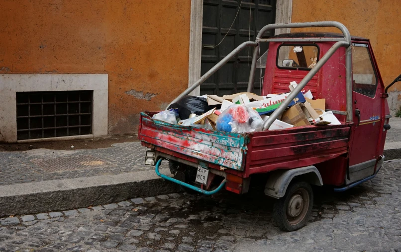 a red dumpster full of junk on a cobblestone street