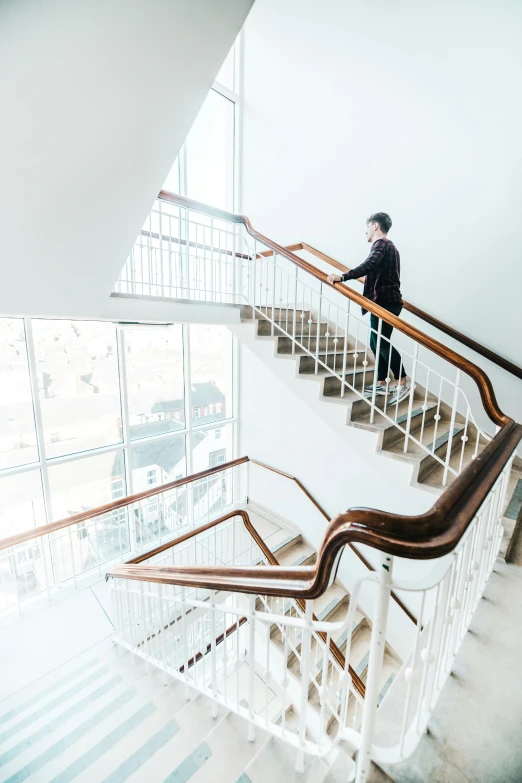 a man stands on an iron stair railing next to a window