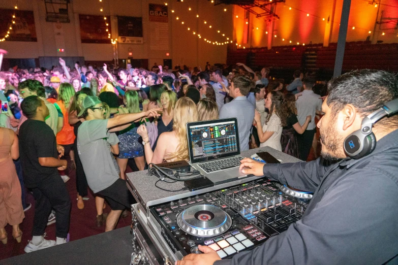 a dj standing at a dj booth using a sound board