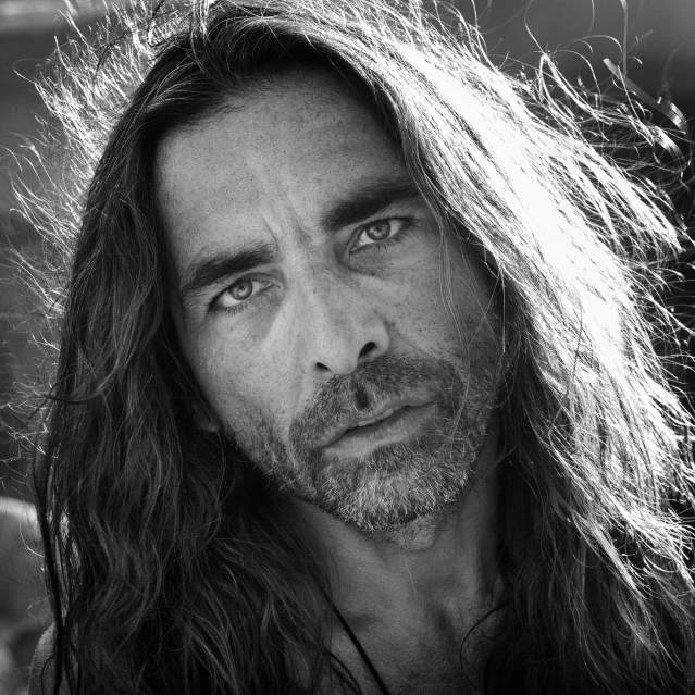 black and white pograph of long haired man staring