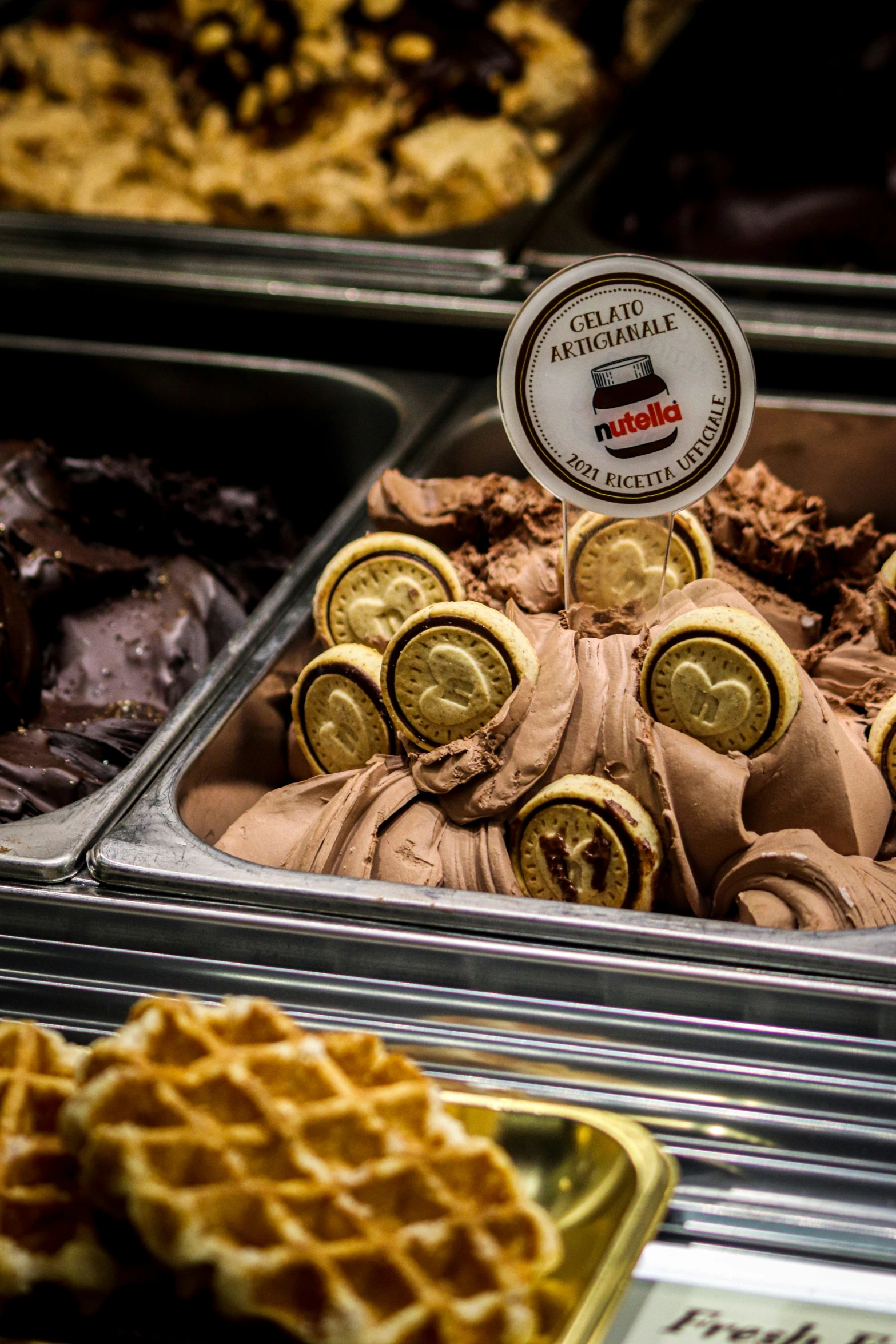 waffles in a display case with chocolate covered donuts