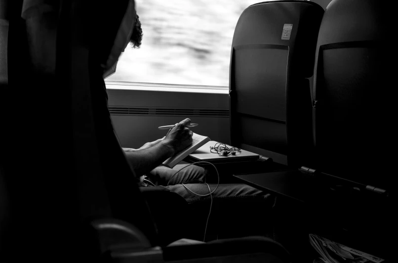 a view of a man using his laptop on a train