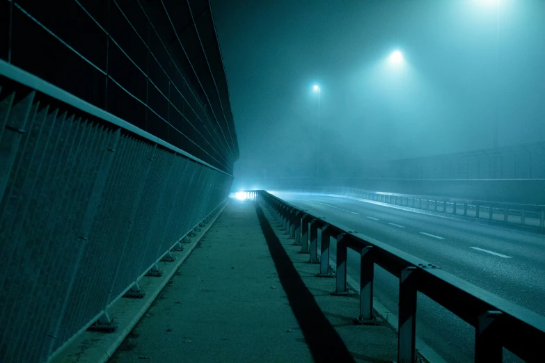 fog covers the walkway of a freeway in an empty parking lot