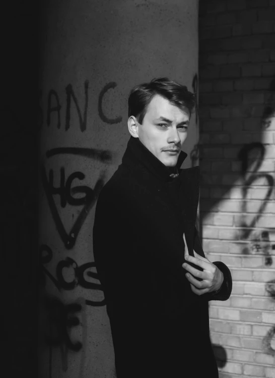 a man in black is standing near graffiti