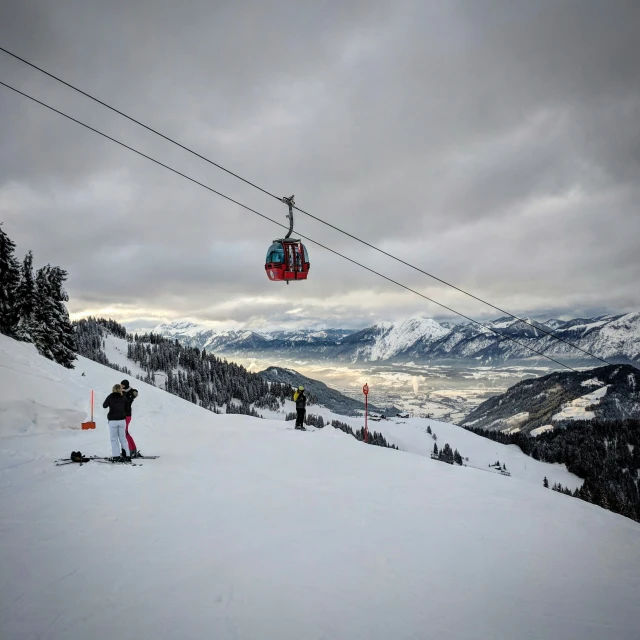 skiers are coming down a hill while holding onto a cable