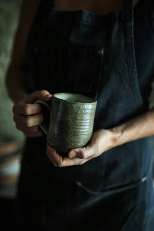 the person in the apron is holding the coffee cup