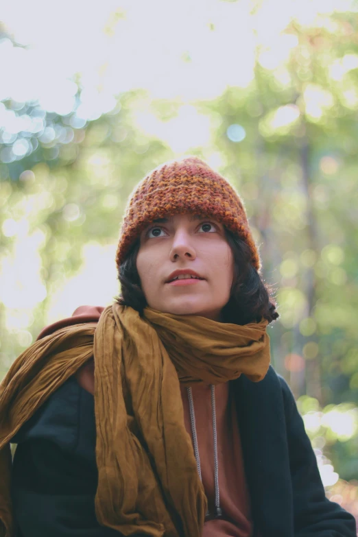 a woman is wearing a hat and scarf in the woods