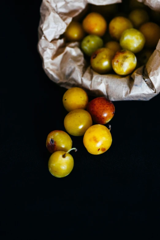 some apples in a brown paper bag on the ground