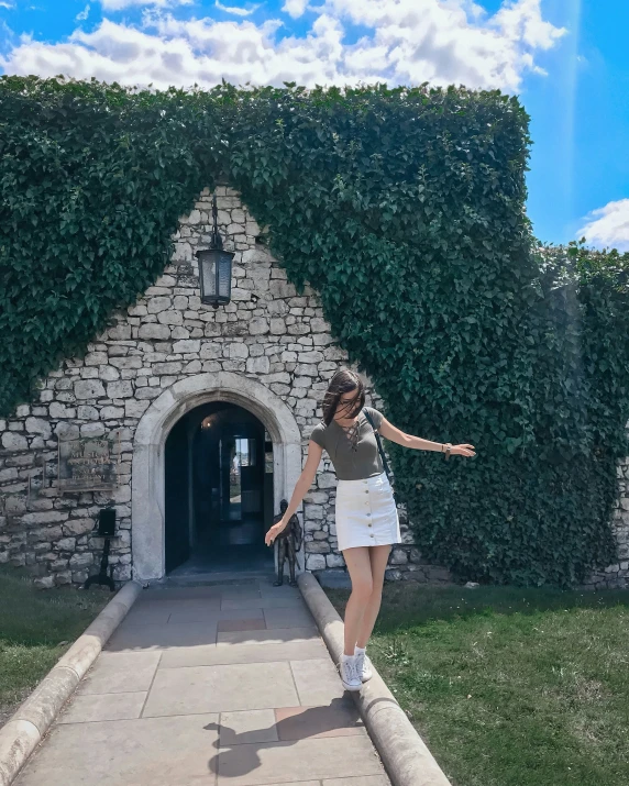 woman walking in front of a building with vines growing on it