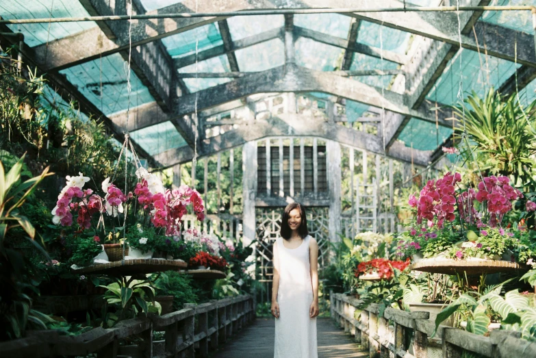 a bride stands in a greenhouse with many flowers