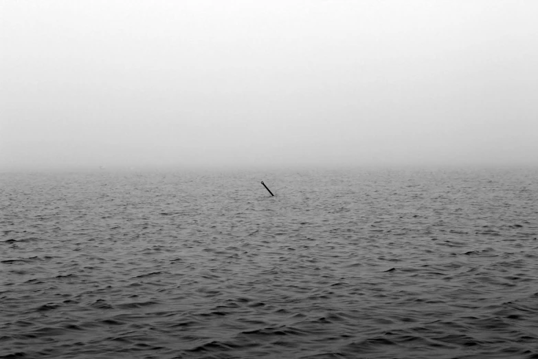 lone sailboat in hazy ocean water on foggy day