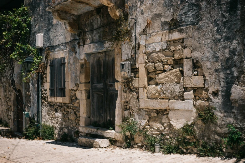 a small stone house with green plants on the side of it