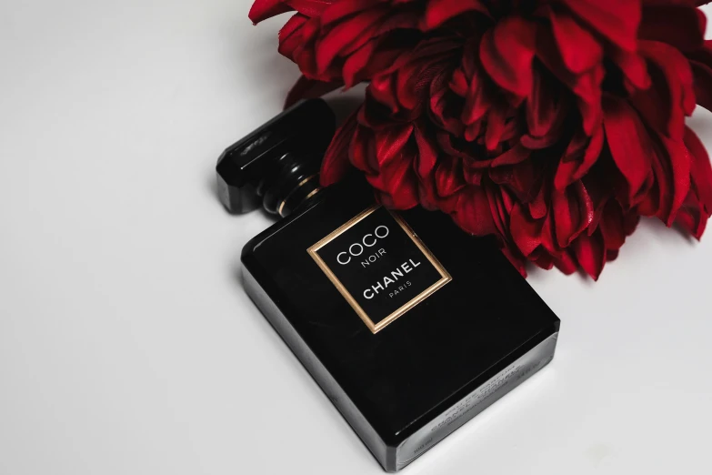 a bottle of perfume sits on top of a flower