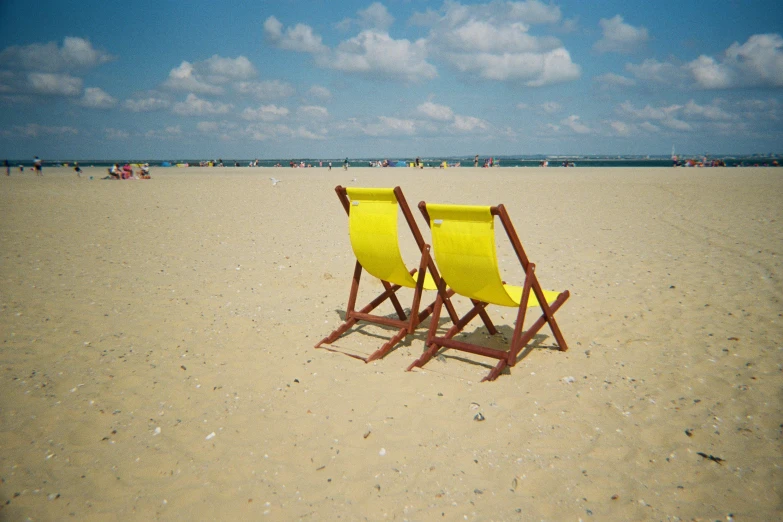 two chairs sitting in the sand by a beach