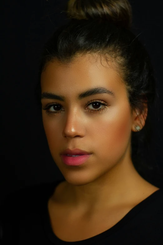 a woman with bun in her hair and dark background