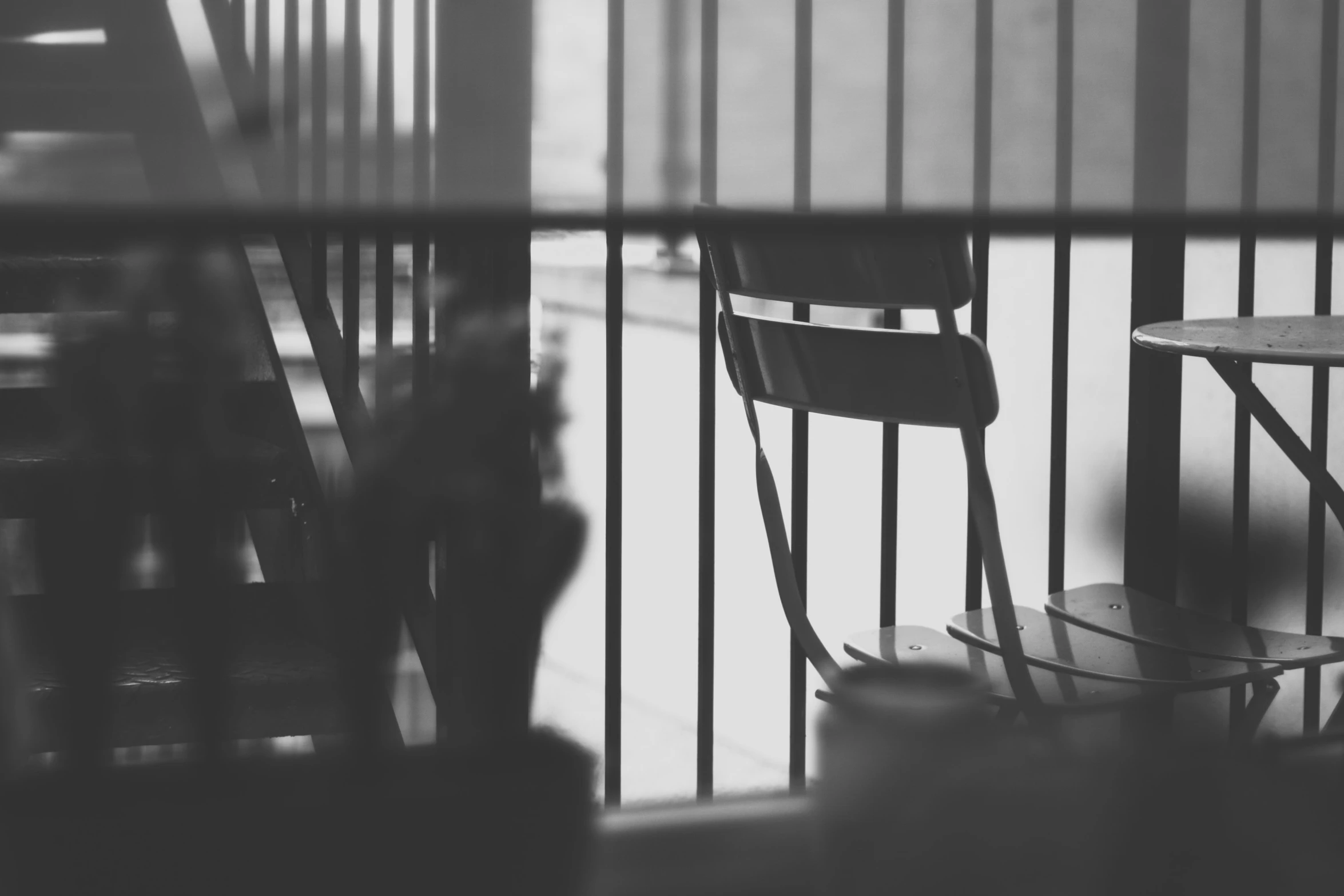 three chairs sitting on a bench near a table and railing