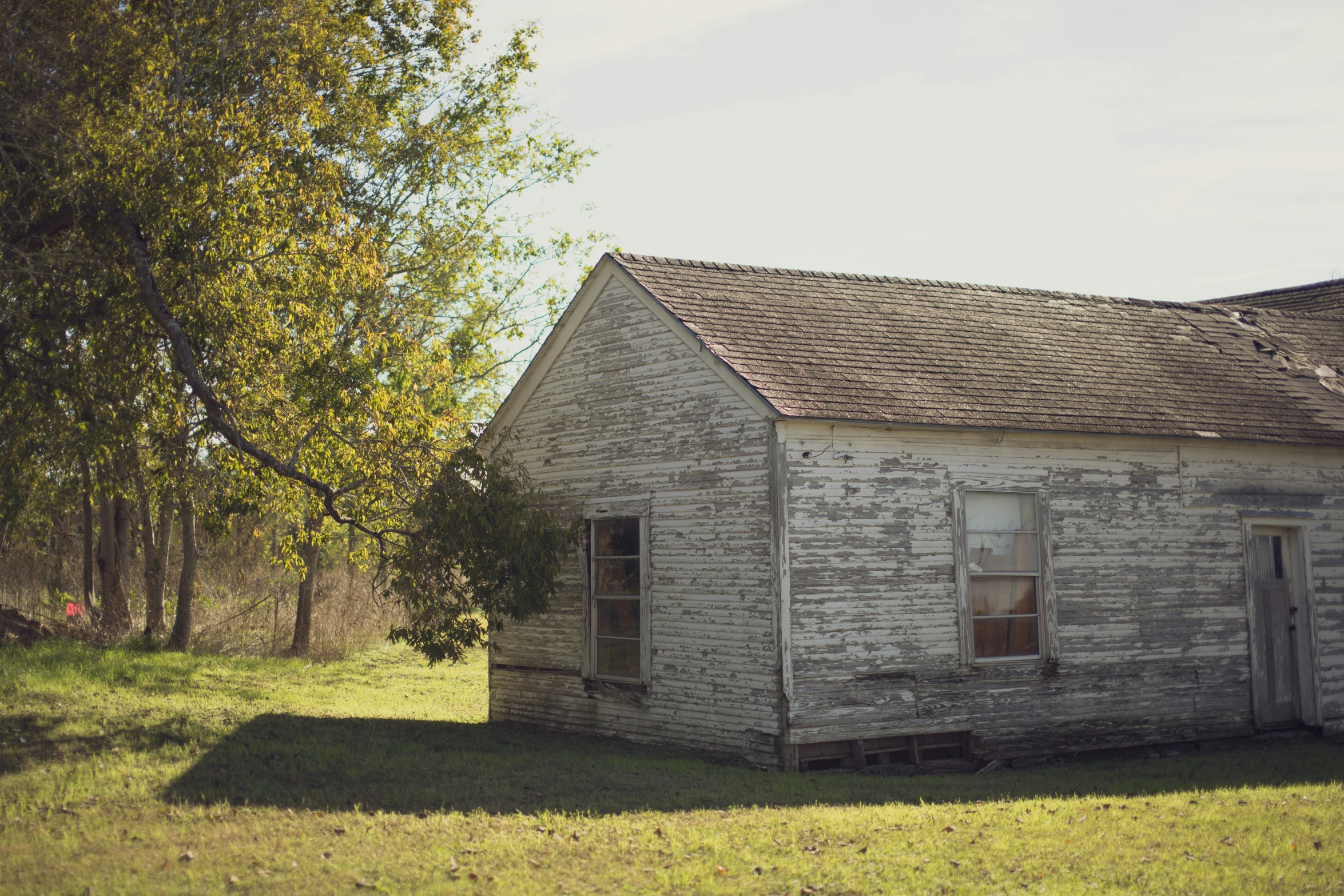 an old run down building sits in the middle of a field