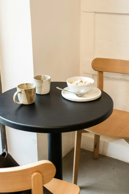 two cups are set at the black table with brown chairs