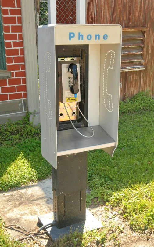 a phone box on a cement slab in the grass