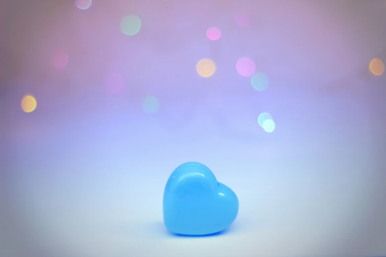 a small blue heart shaped object sitting on a white surface