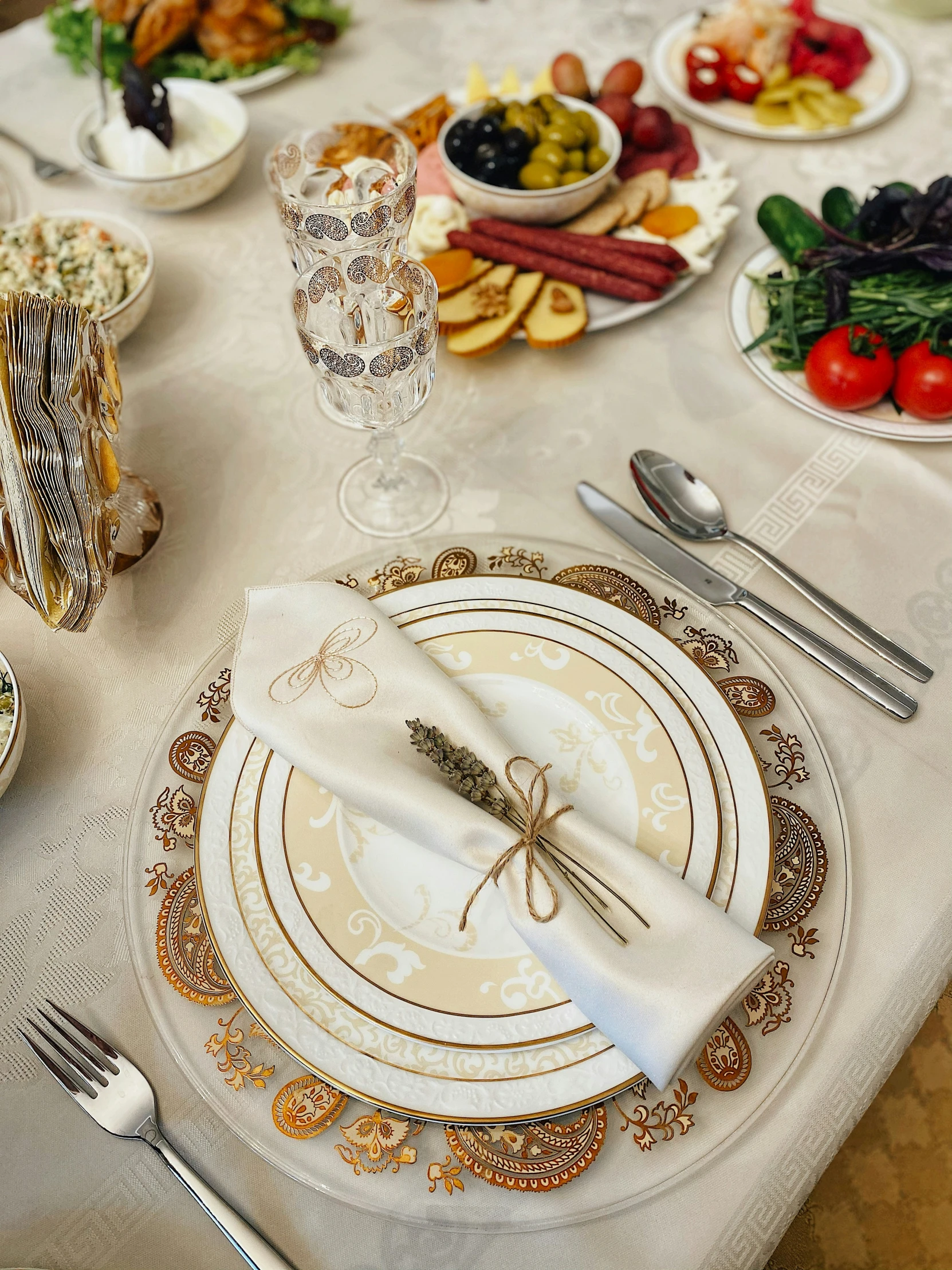 a dining table set for a meal with a white and gold table cloth