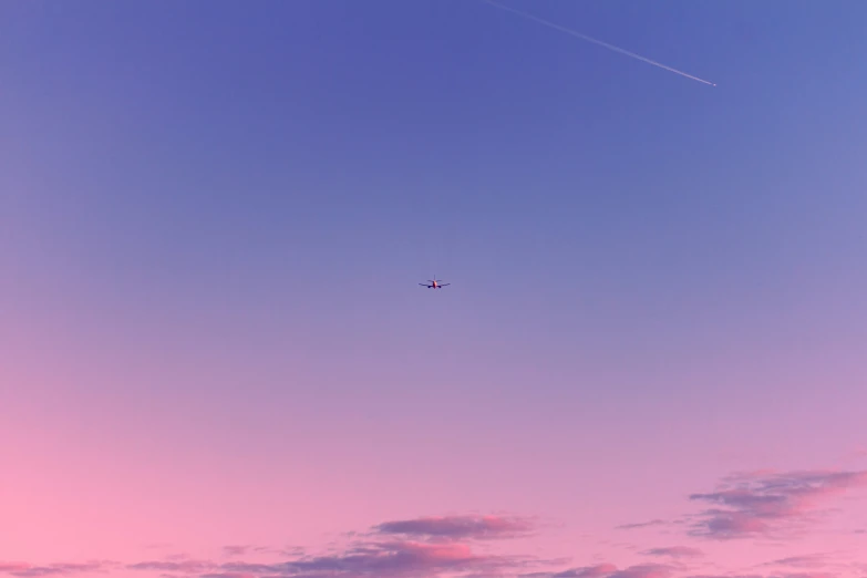 a plane flies high in the sky in the sunset