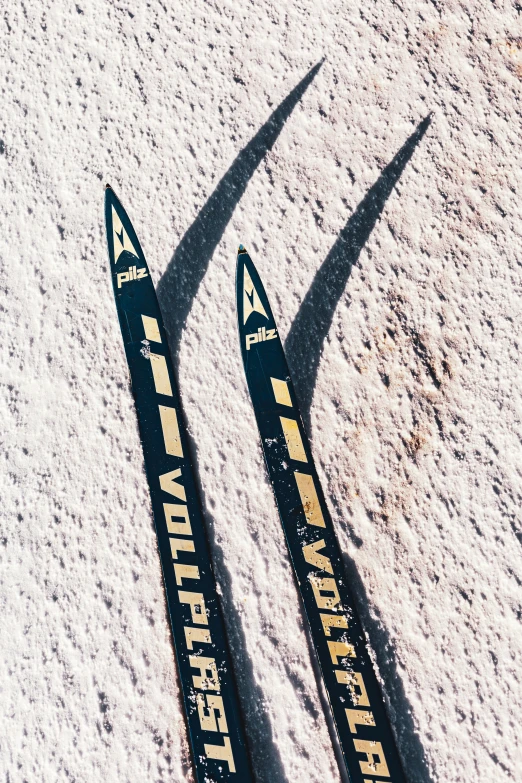 two skis laying on snow covered ground in the sunlight