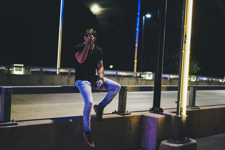 the man is sitting on the cement wall by the street