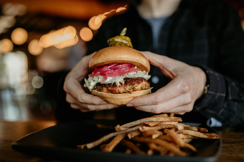 a man holds a large hamburger and french fries