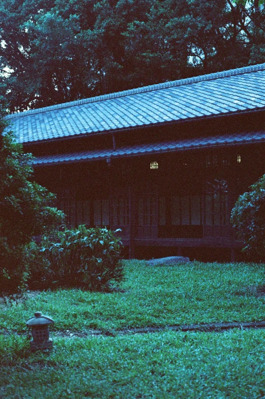 the green grass and trees in front of a small wooden building